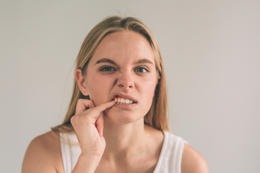 woman with finger in teeth in pain