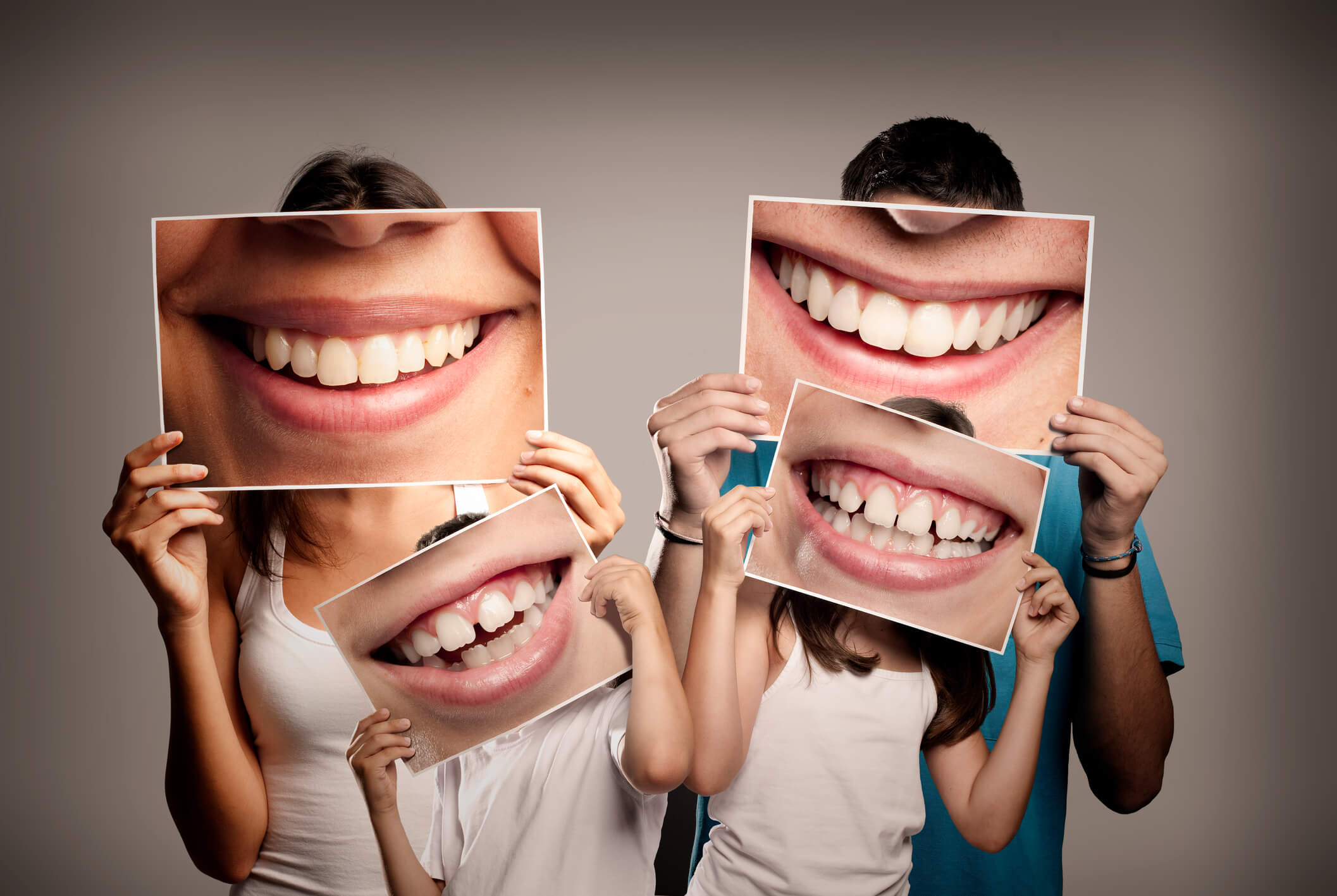 four people holding close up pictures of smiles in front of them