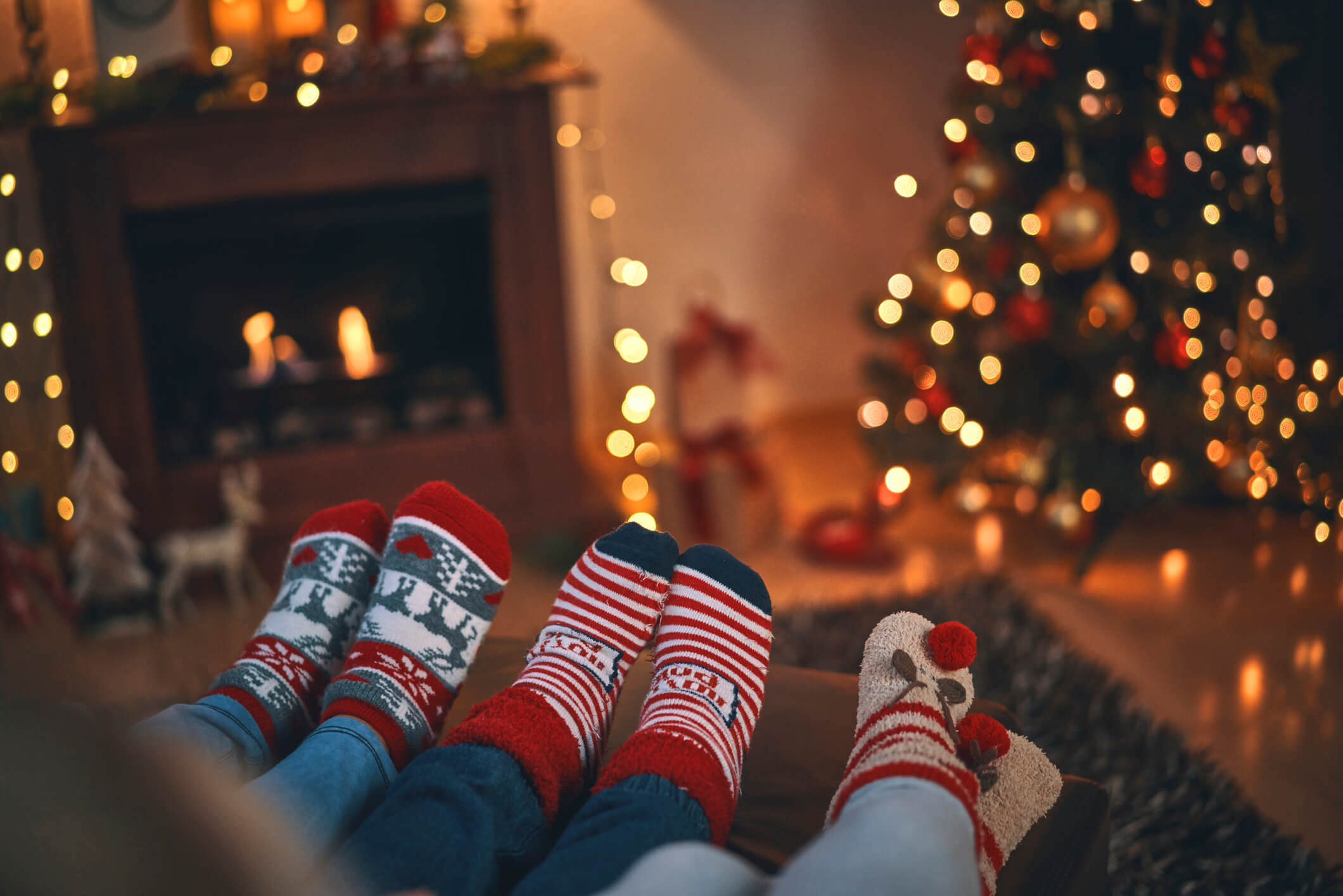 three people with christmas socks on in front of christmas tree