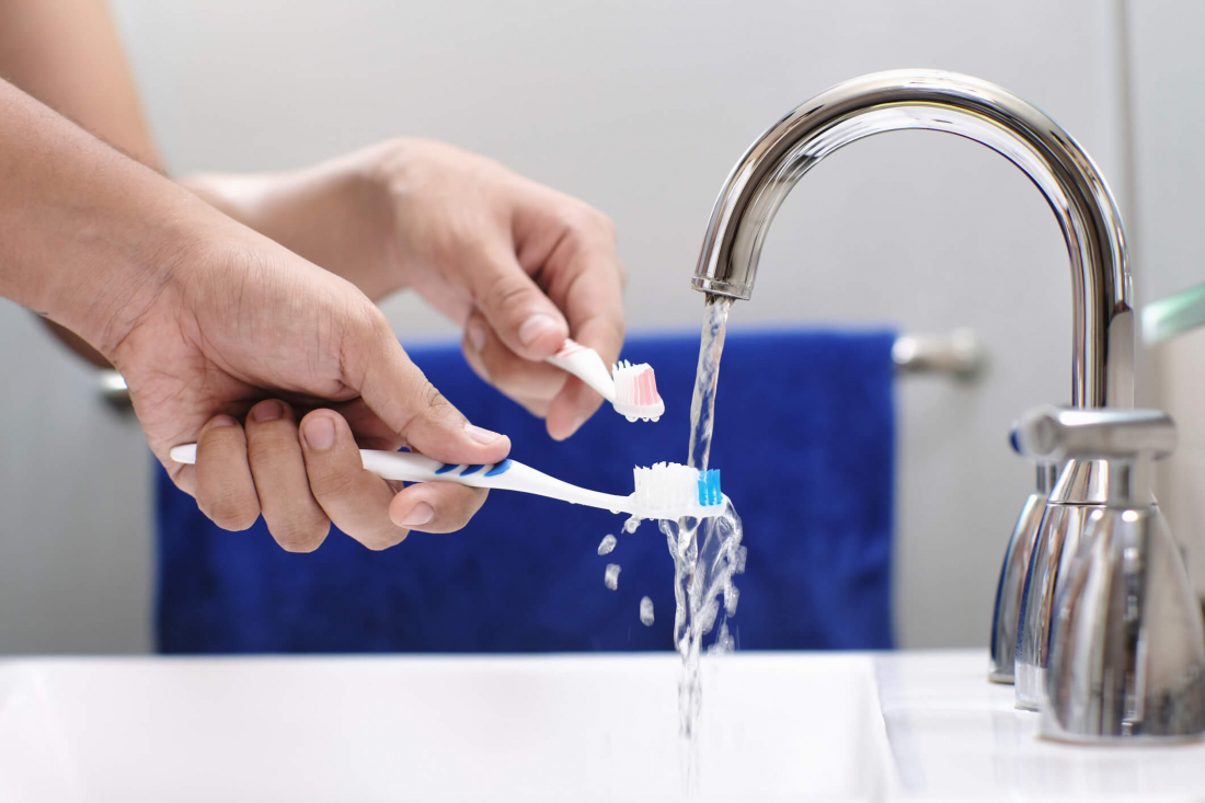 toothbrushes under running water