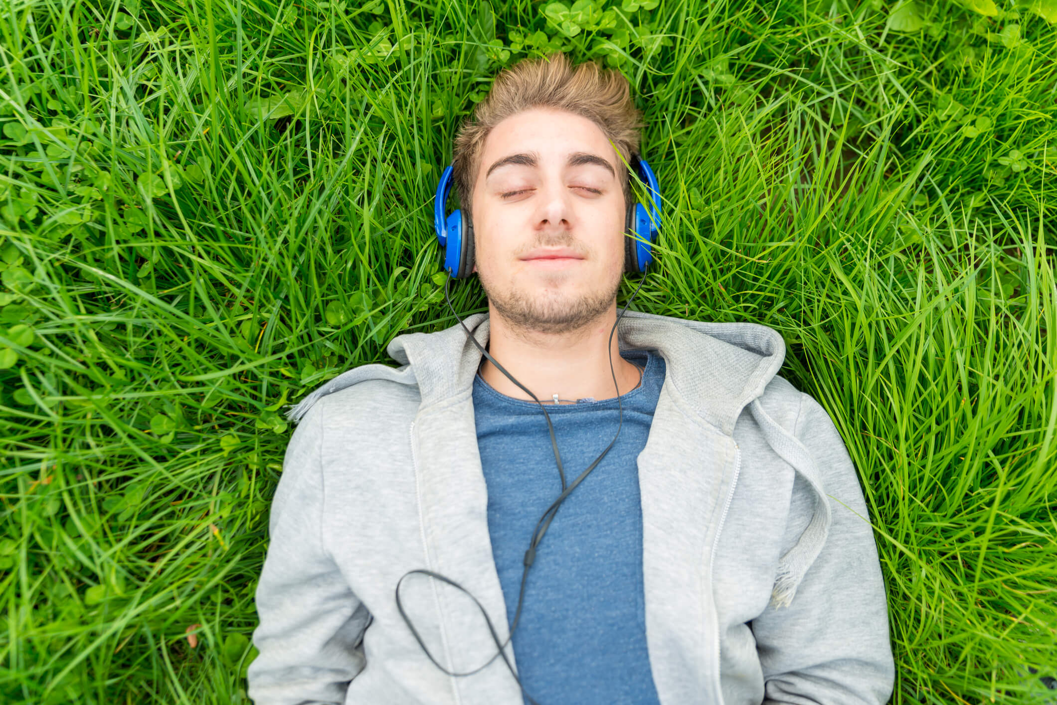 eyes closed man with headphones laying in grass