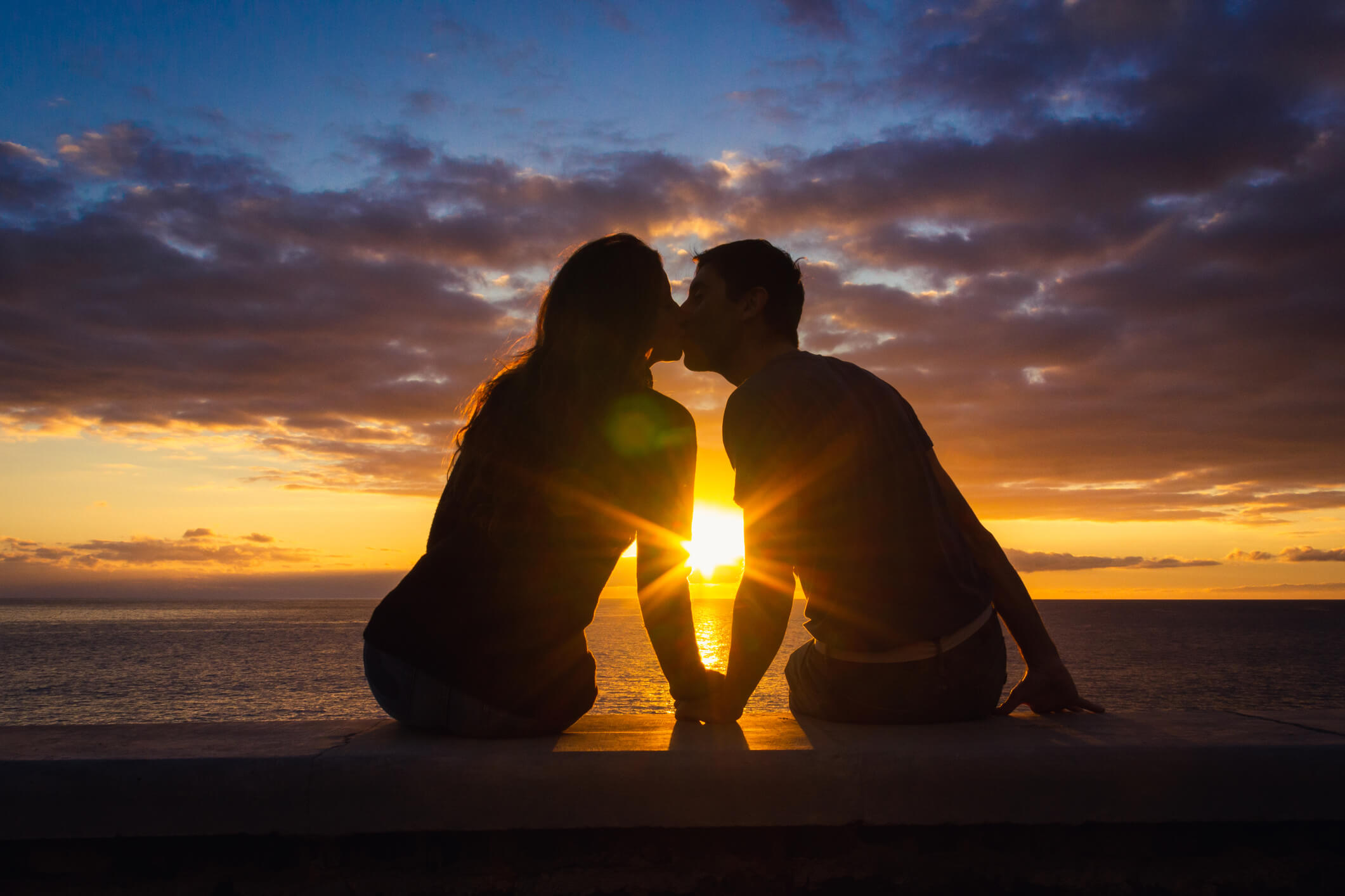 couple kissing in front of the sun