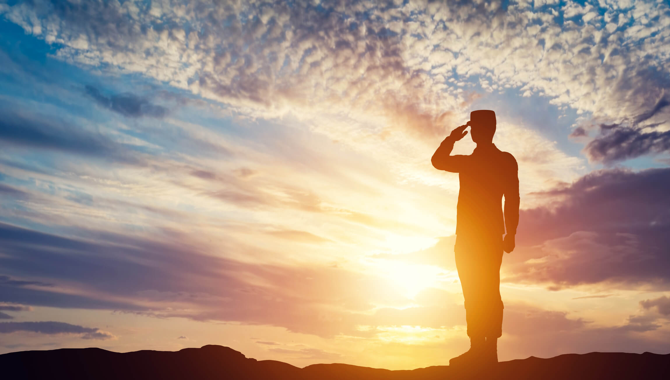 veteran saluting in front of sun