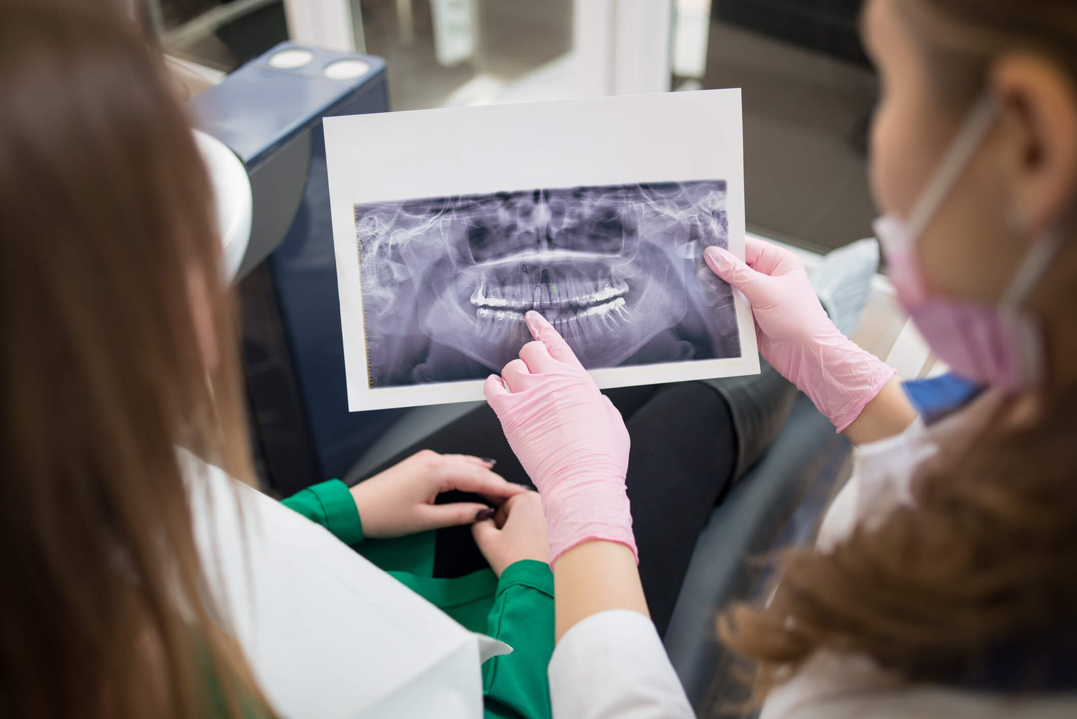 two people pointing to x-ray of teeth