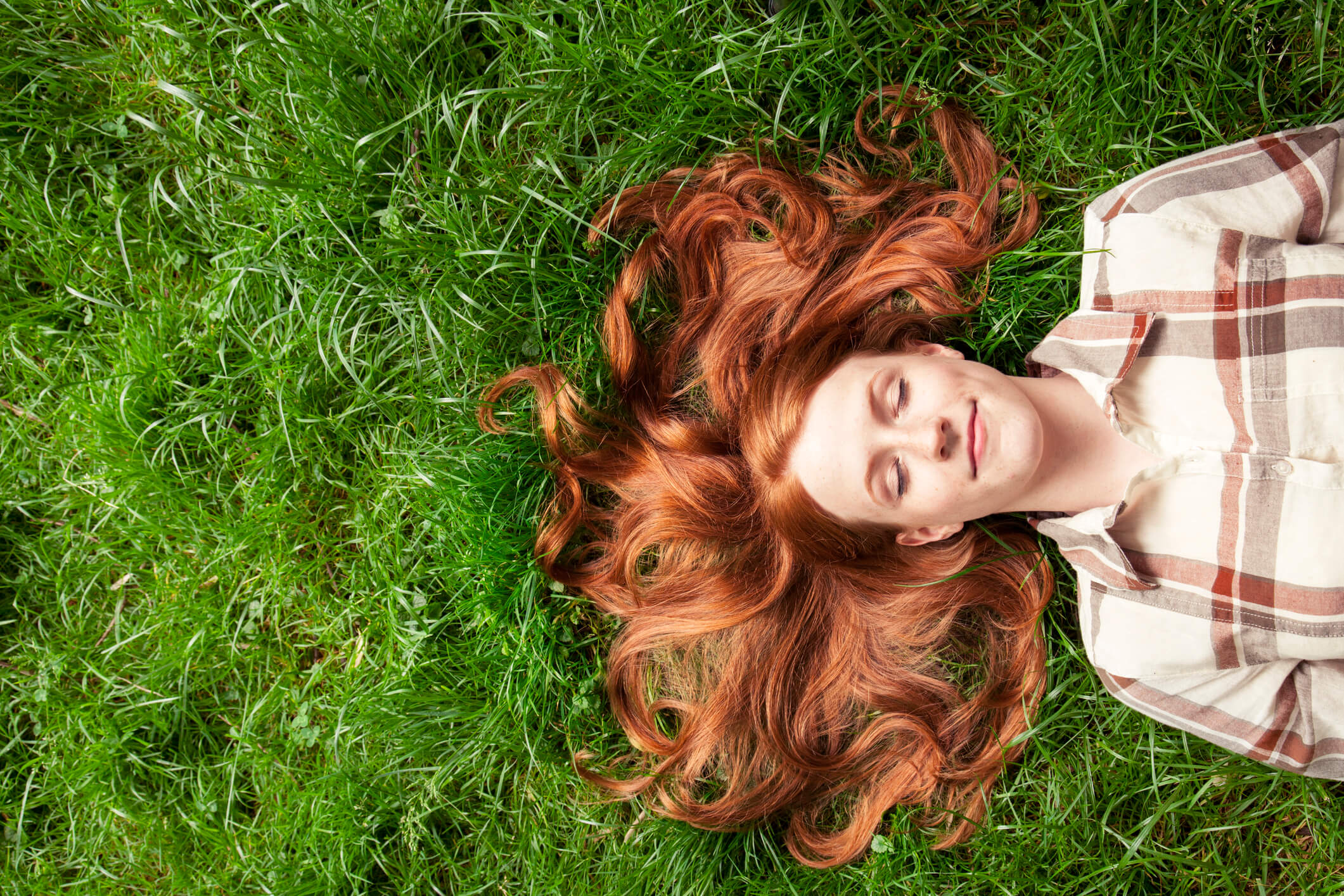 woman with eyes close laying in grass