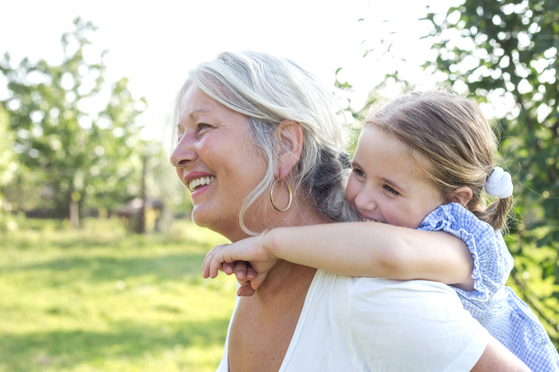 senior woman carrying child on her back