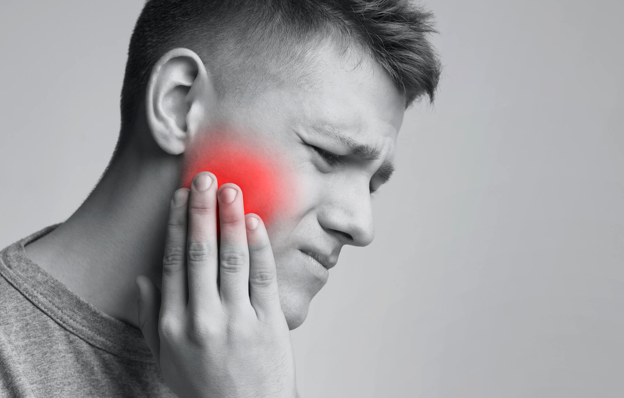 wincing man holding jaw in pain