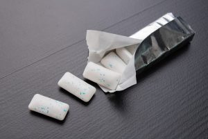 Chewing gum on the table. Mint refreshing tablet in a silver package. Dark background.