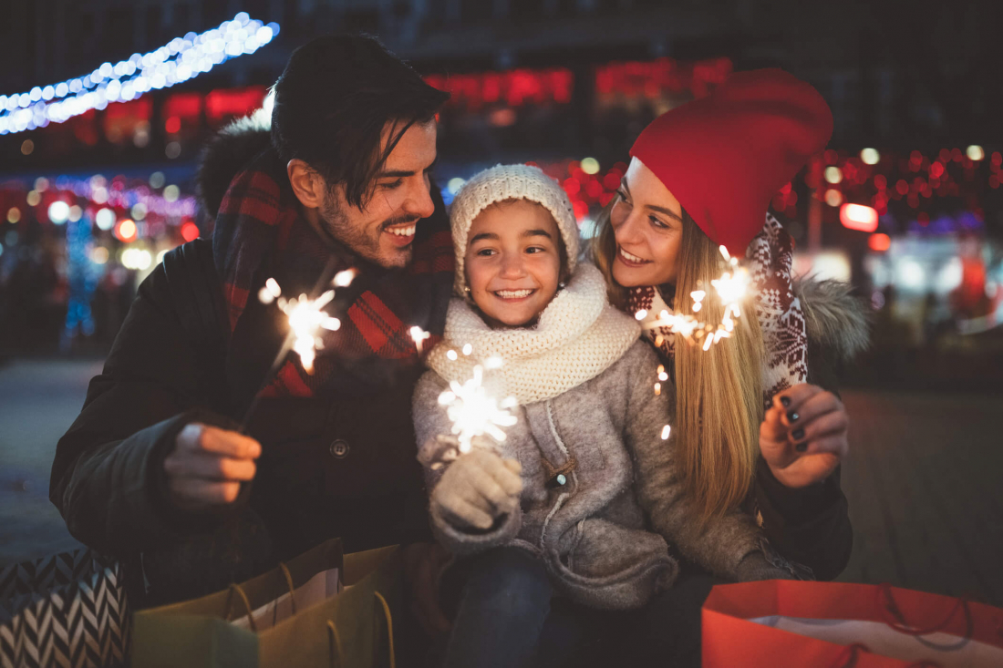 smiling man, woman, and child holding firecrackers