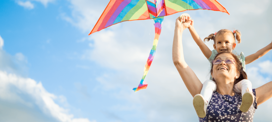 smiling woman flying a kite with child