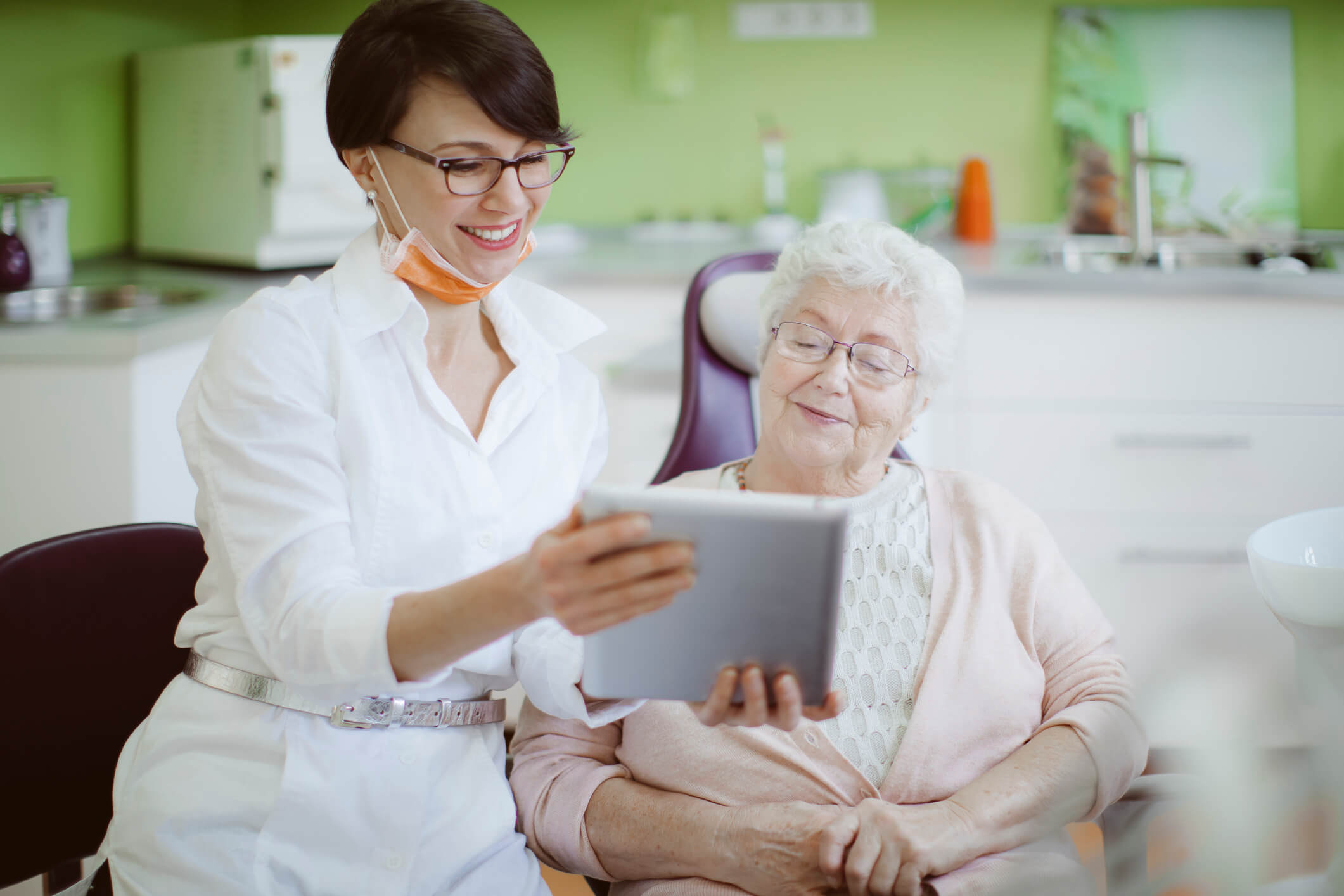 smiling woman with device showing to senior woman