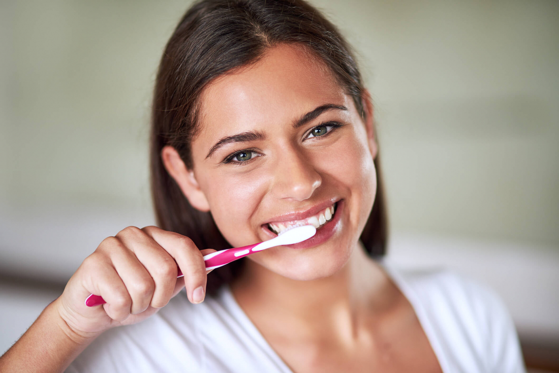 smiling woman brushing teeth