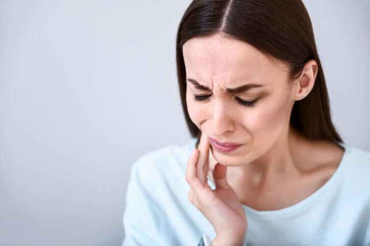 woman wincing in pain holding jaw