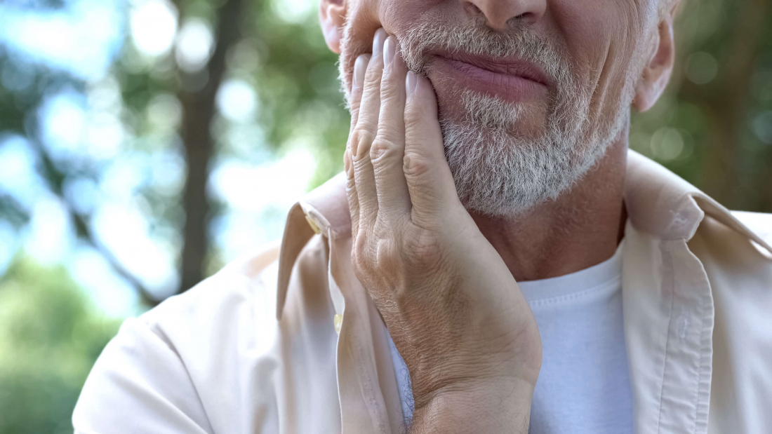 senior man holding jaw in pain