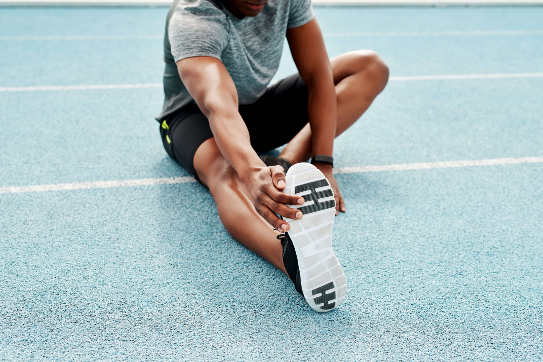 man on ground stretching by touching his toes