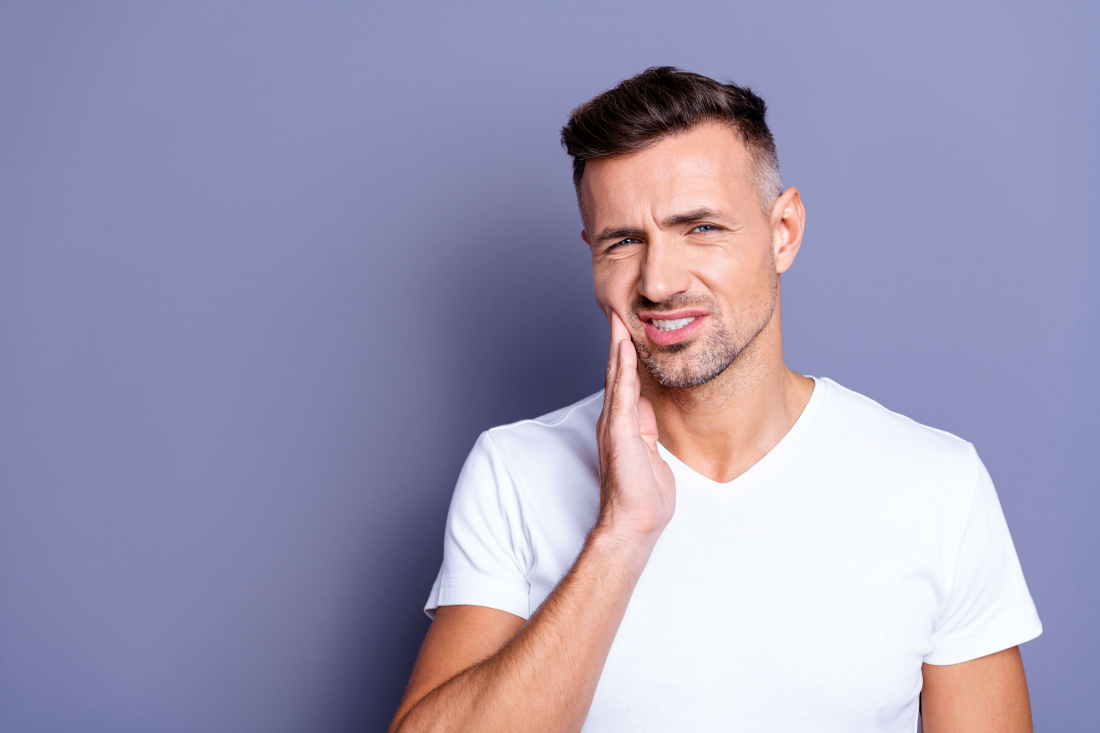 man wincing with hand on jaw