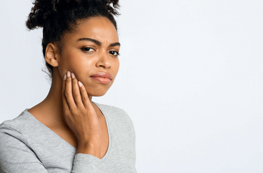 woman holding jaw in pain