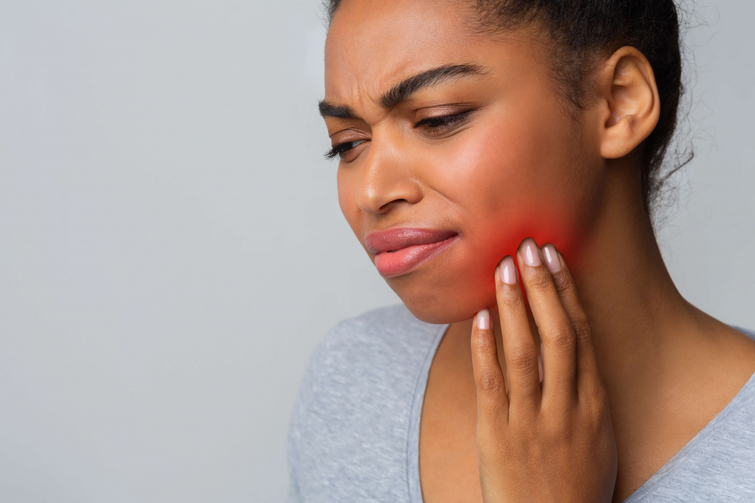 woman holding jaw in pain