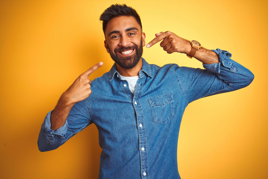 smiling man pointing to his own smile