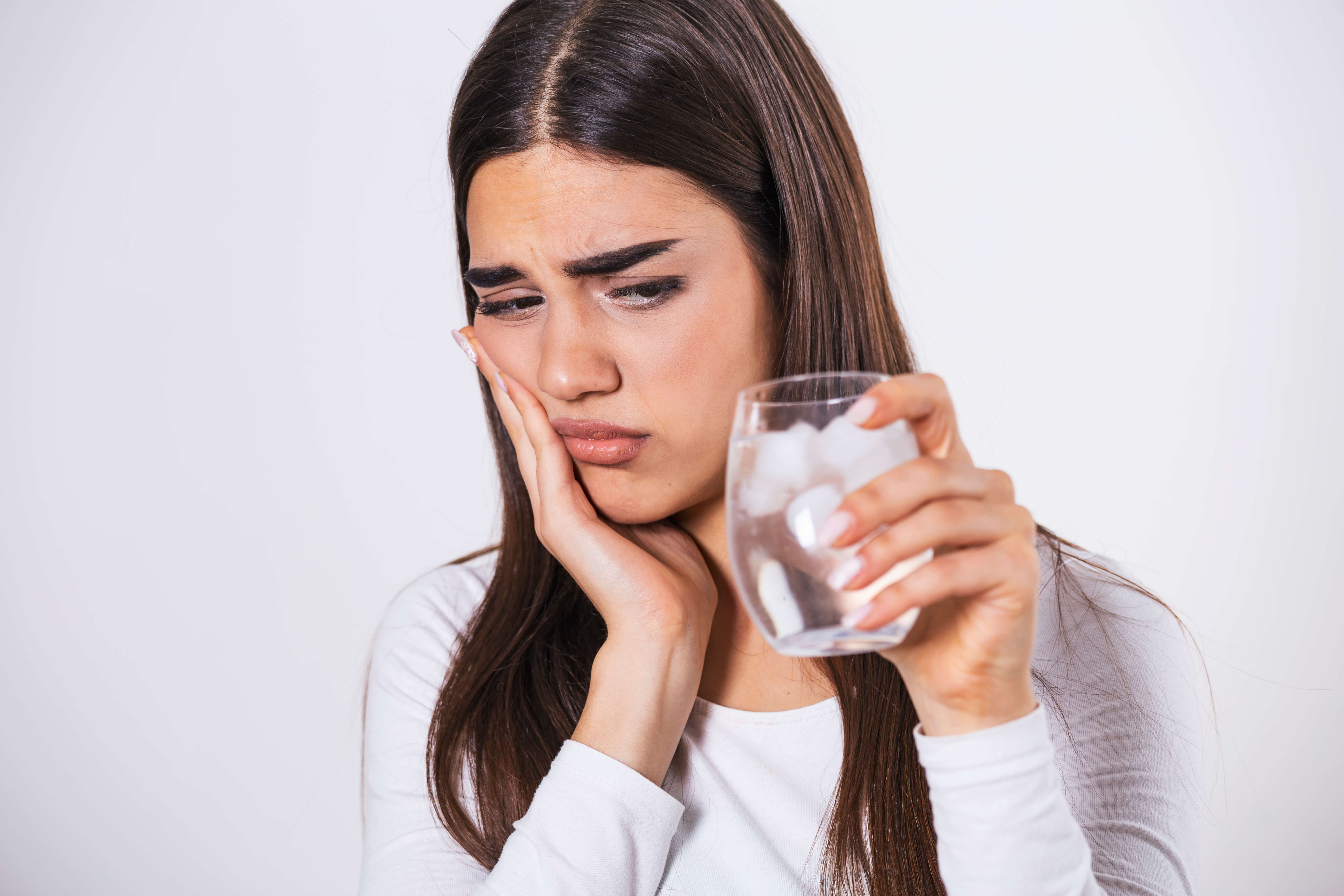 woman holding jaw in pain and holding ice water