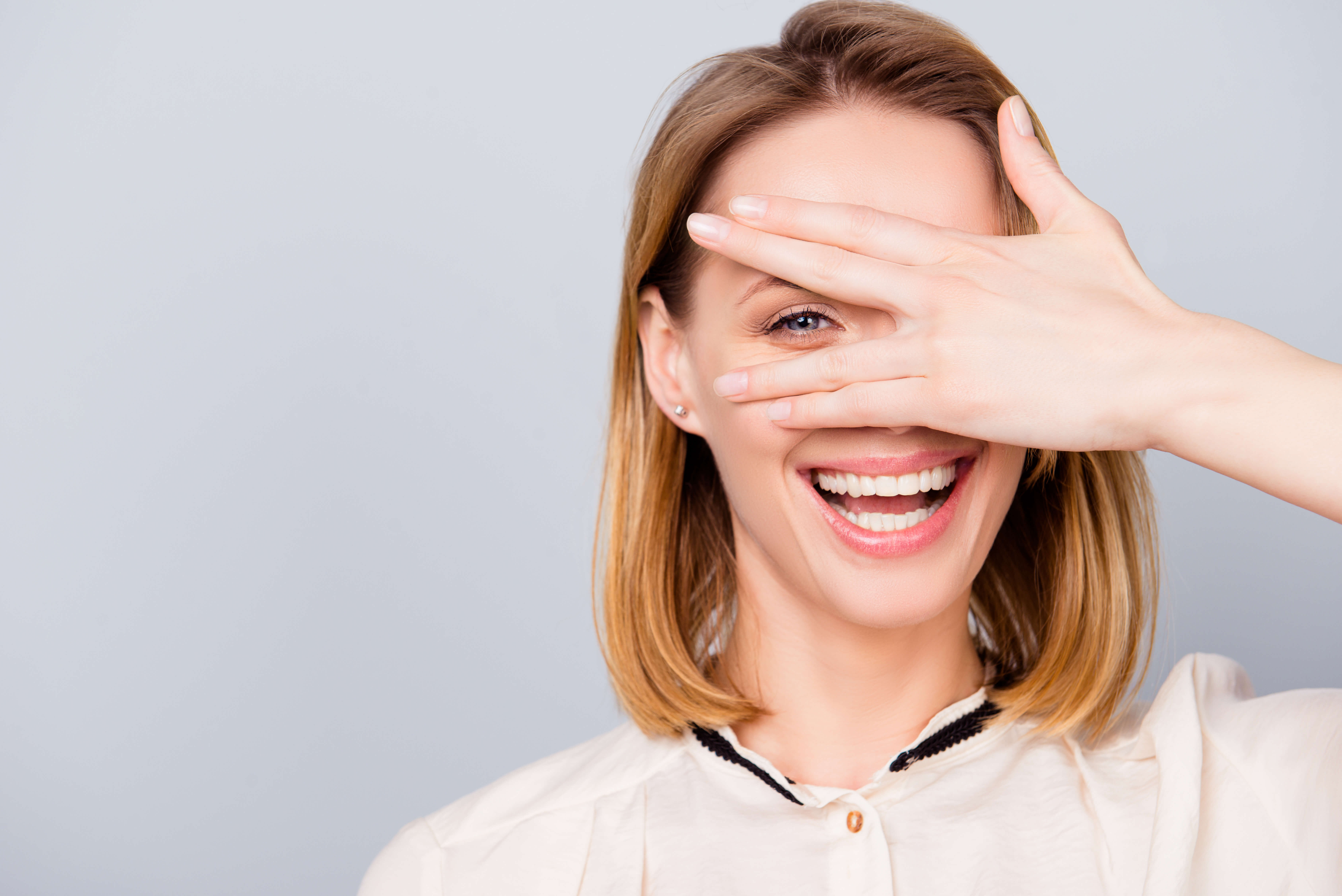 smiling woman covering one eye with hand
