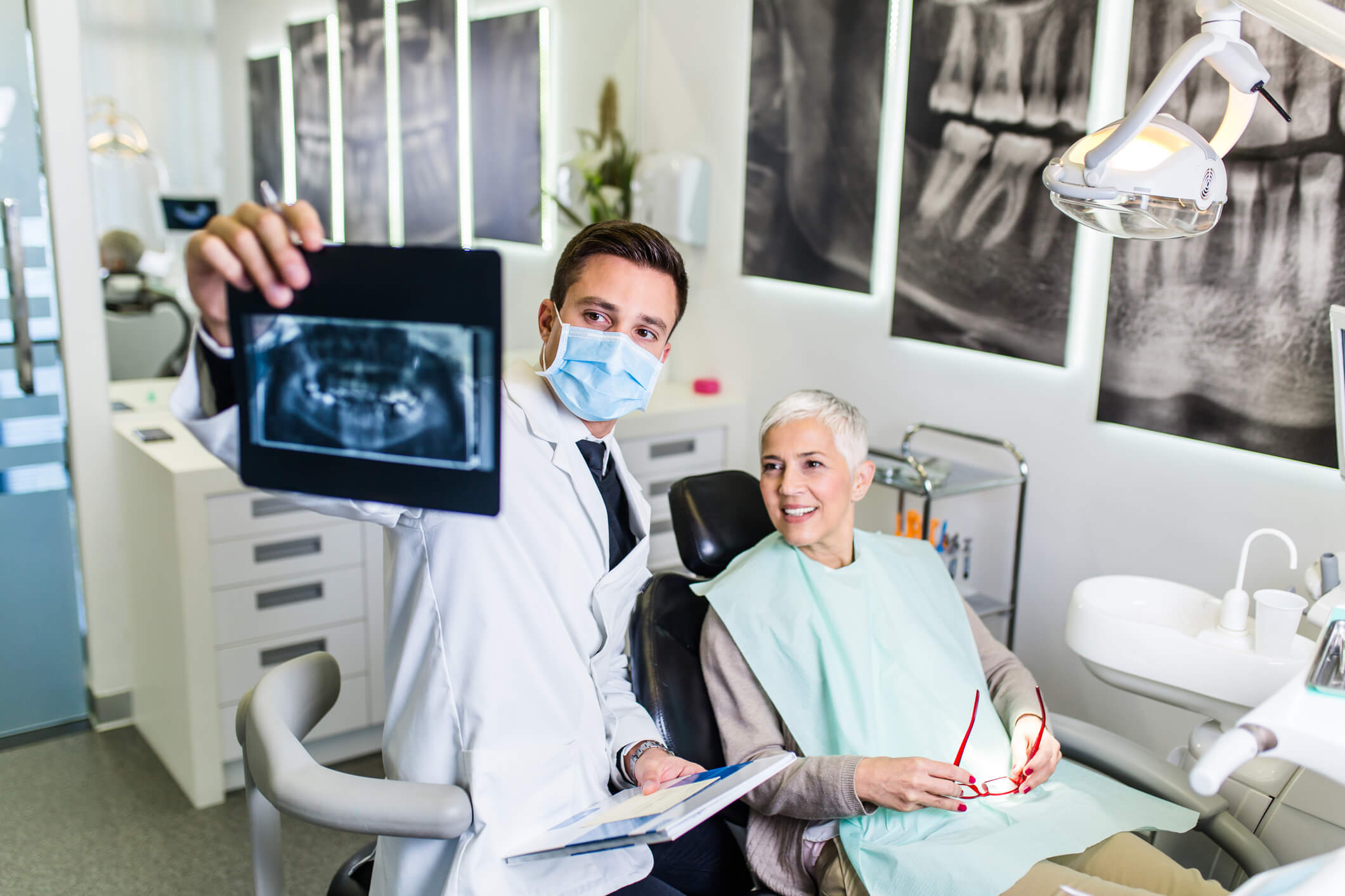 dentist showing X-ray to smiling woman in chair