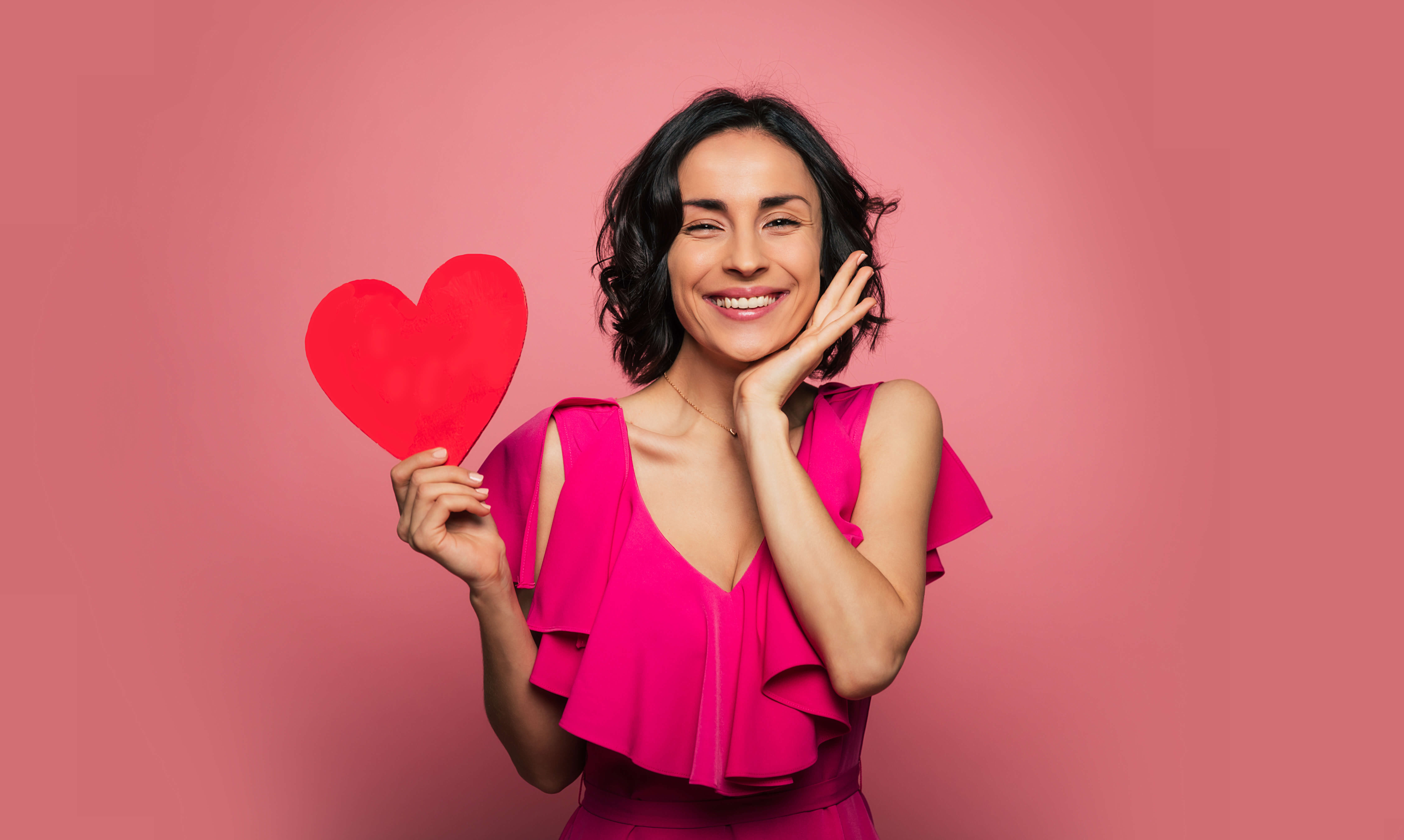 photo of woman smiling while holding a paper heart