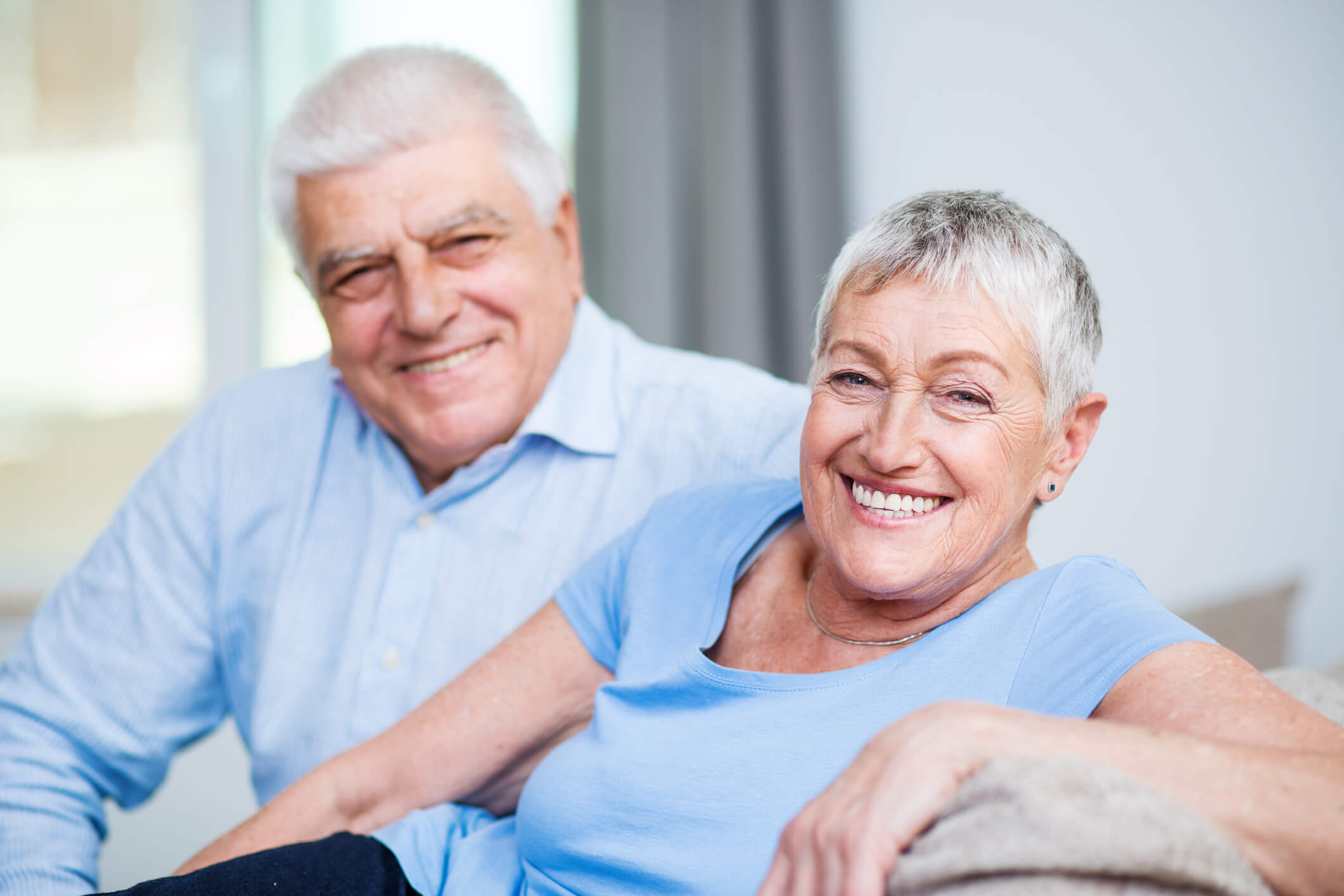 photo of two older adults sitting on couch smiling