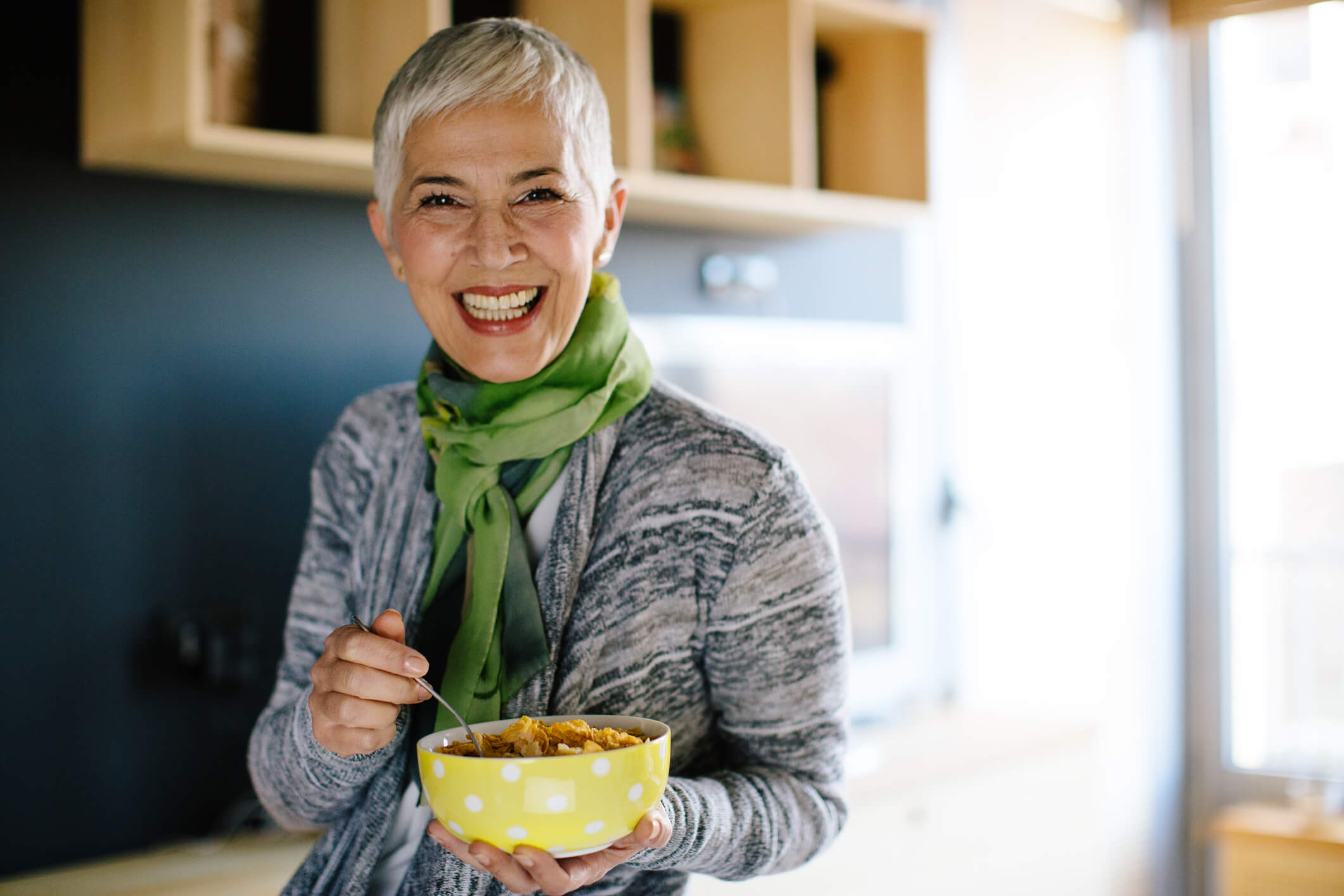 woman with dentures holding a cereal bowl and smiling
