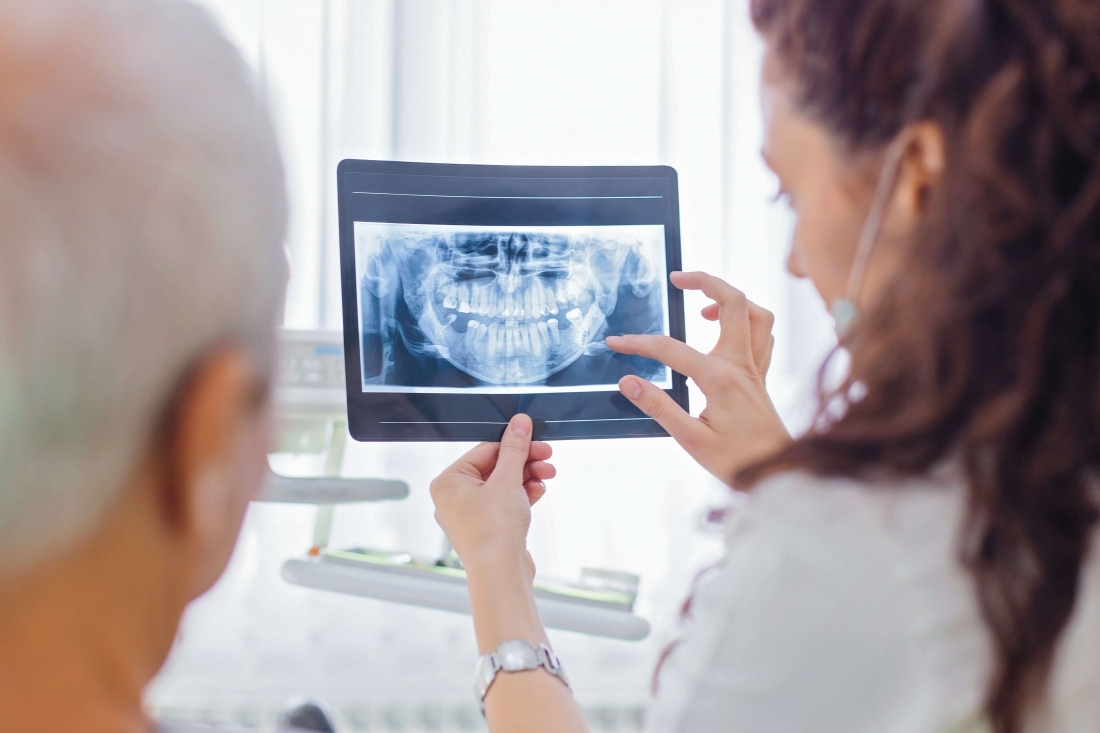 photo of dentist with dental patient reviewing treatment options for root canal vs. filling