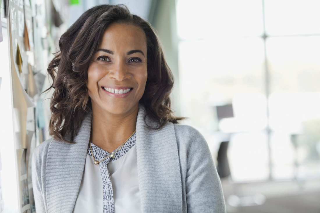 photo of woman with clean dental implants wearing gray shirt smiling