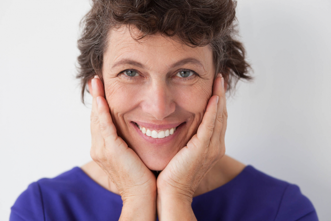 smiling woman in blue shirt holding her face