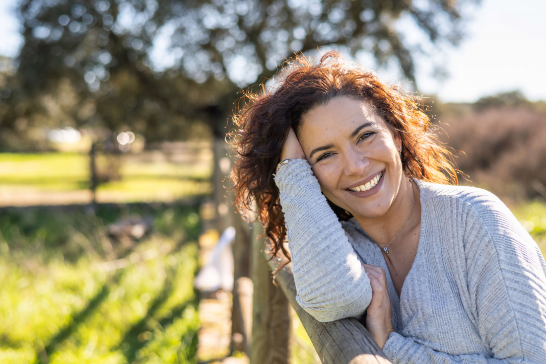woman in gray sweater standing outside and smiling