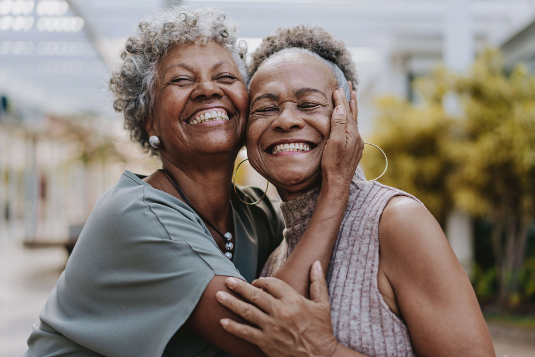 two women wearing partial dentures hugging and smiling