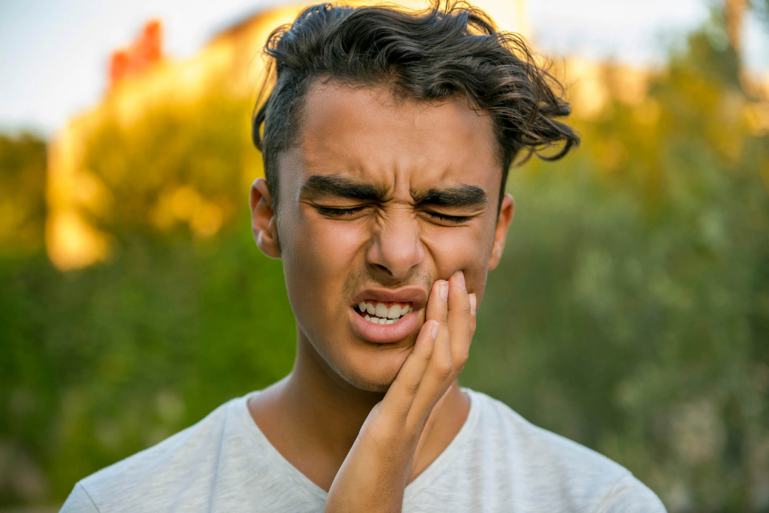 man holding cheek who needs emergency dental pain relief