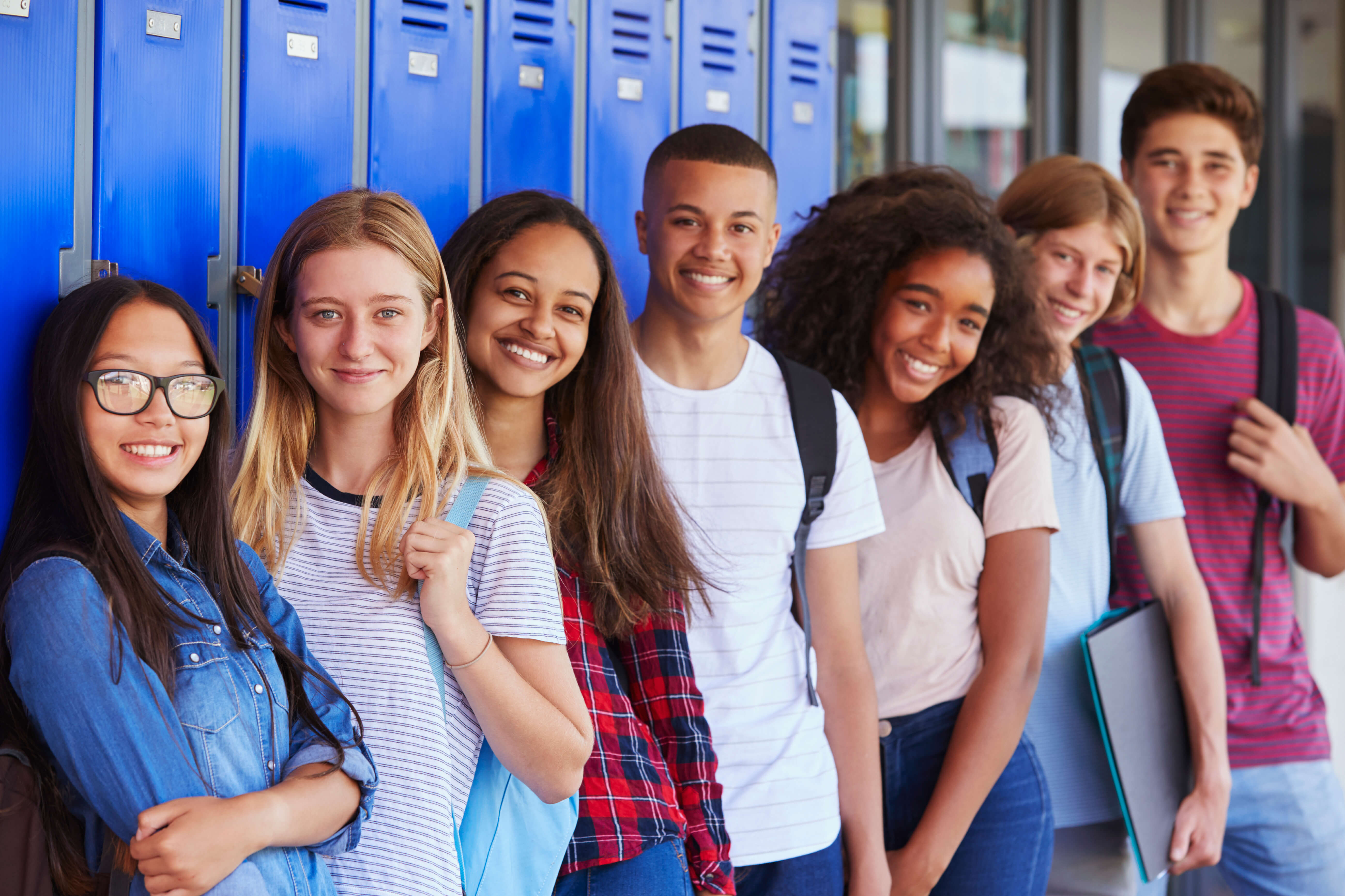 group of teens smiling in front of blue lockers