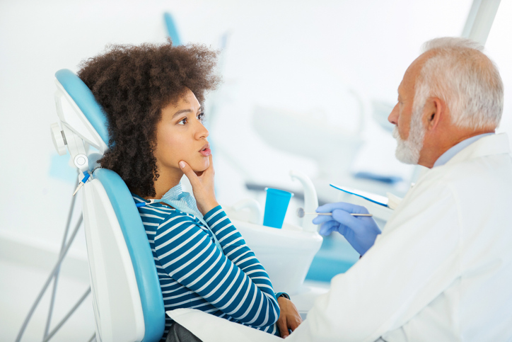 woman holding jaw while at the dentist office