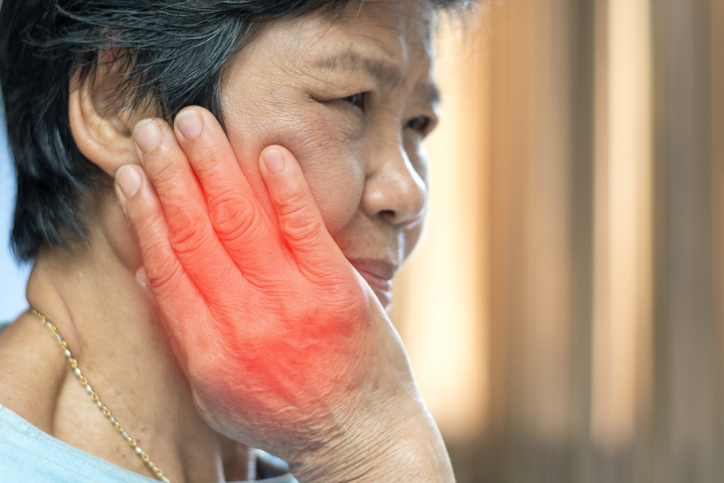 woman holding jaw with red glow on her hand